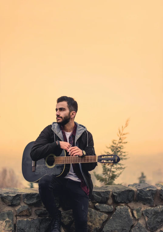 a man in a jacket sitting with his guitar