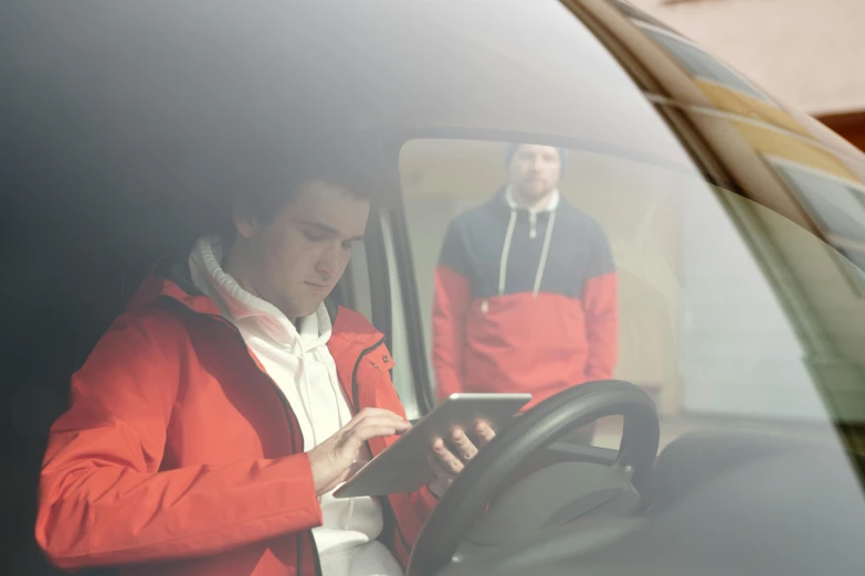 a man standing in front of a vehicle holding a tablet