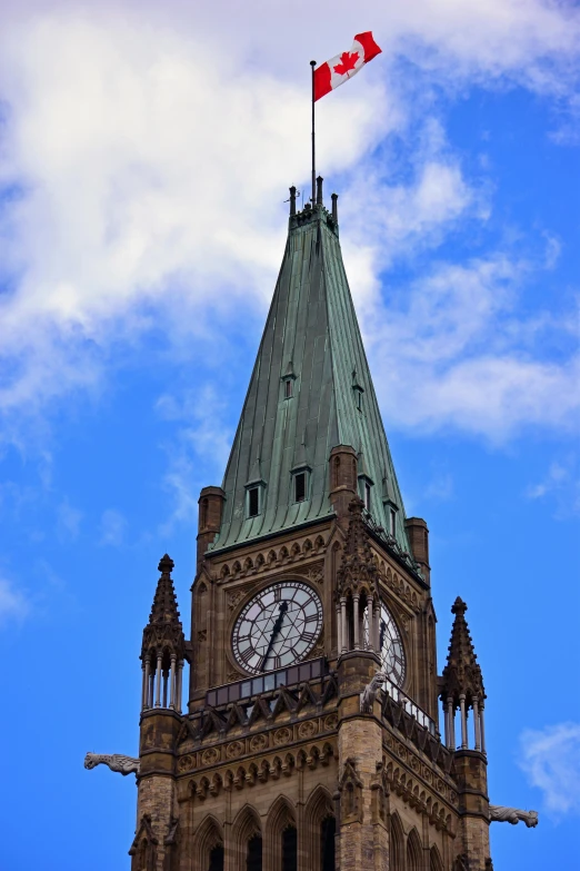an old fashioned clock tower with a canadian flag on top