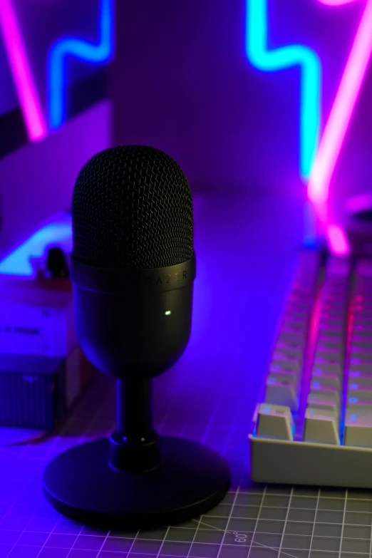 a blue microphone sits next to an illuminated keyboard