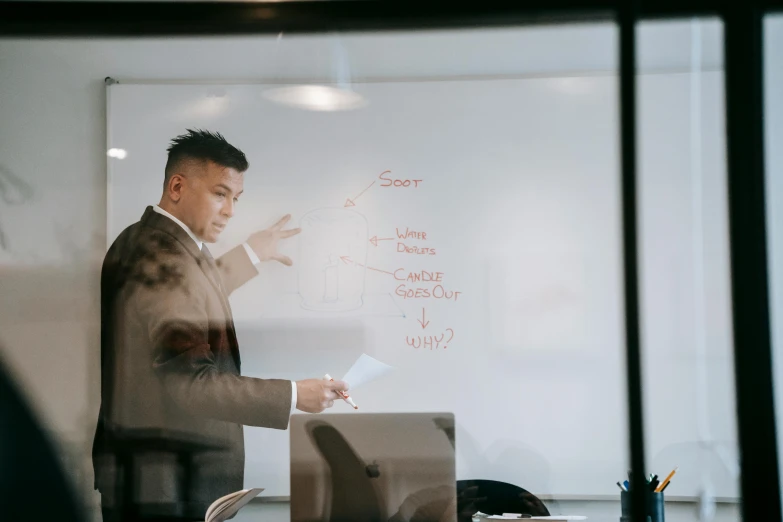 a man is pointing at a white board