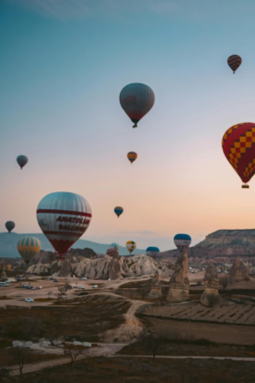 several colorful  air balloons over a desert landscape