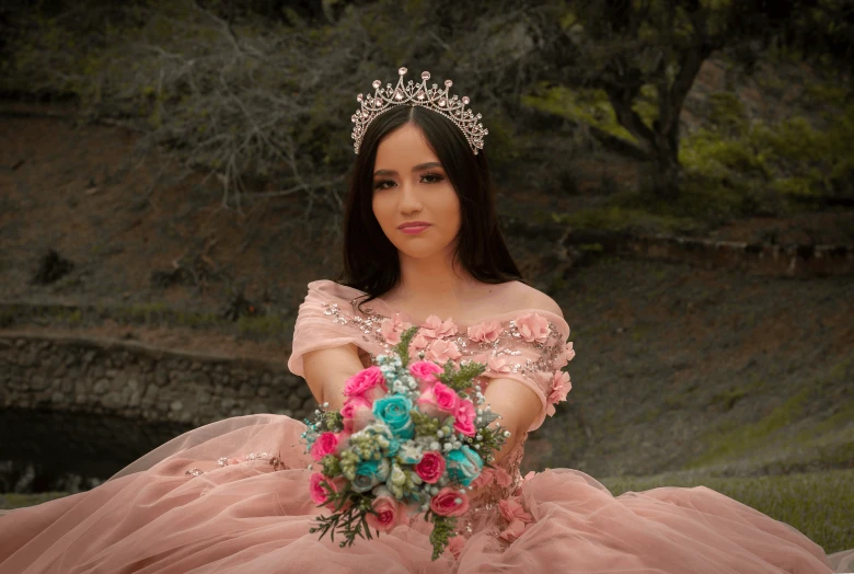 a woman wearing a ball gown holding a bouquet of flowers