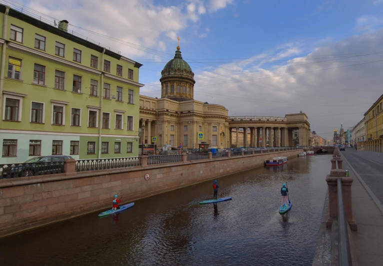 three people are standing on small boats in the middle of a canal