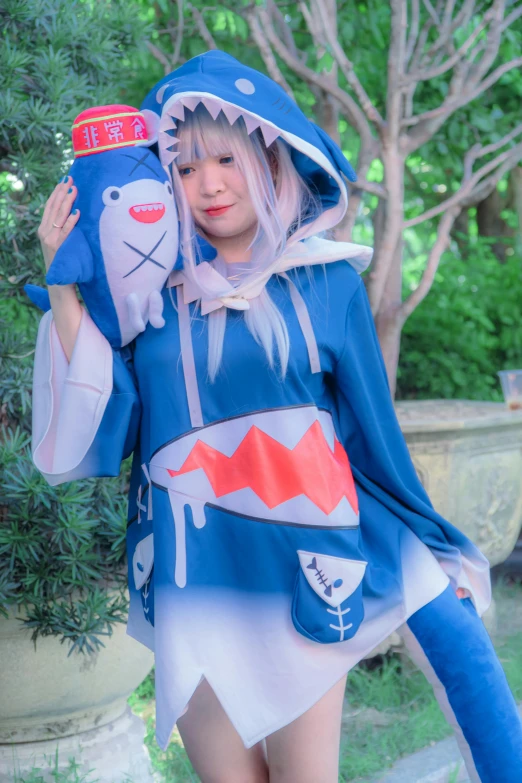 an asian girl holding up a blue stuffed animal