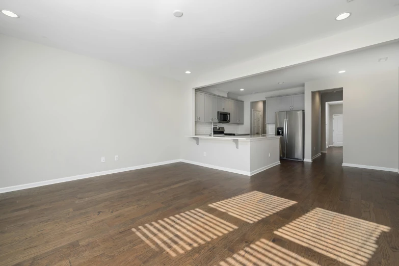 an empty, clean apartment shows an open kitchen and living room with new appliances