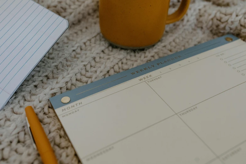 a calendar, pen and mug on a blanket