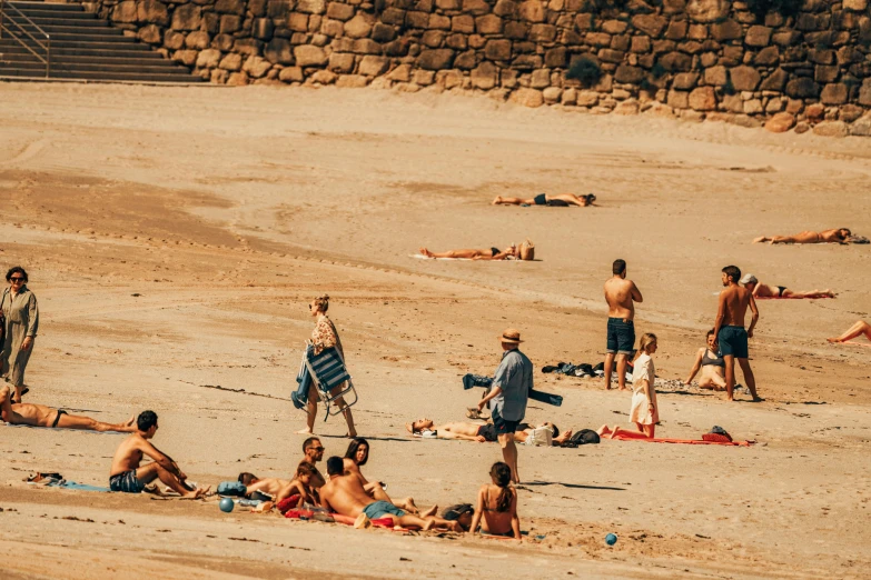 people are sitting and standing at the beach