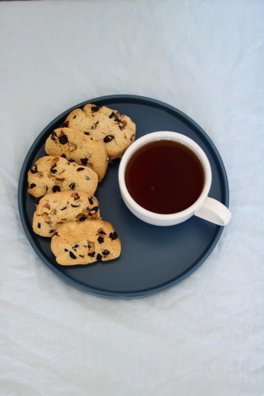 a blue plate with cookies and a cup of tea