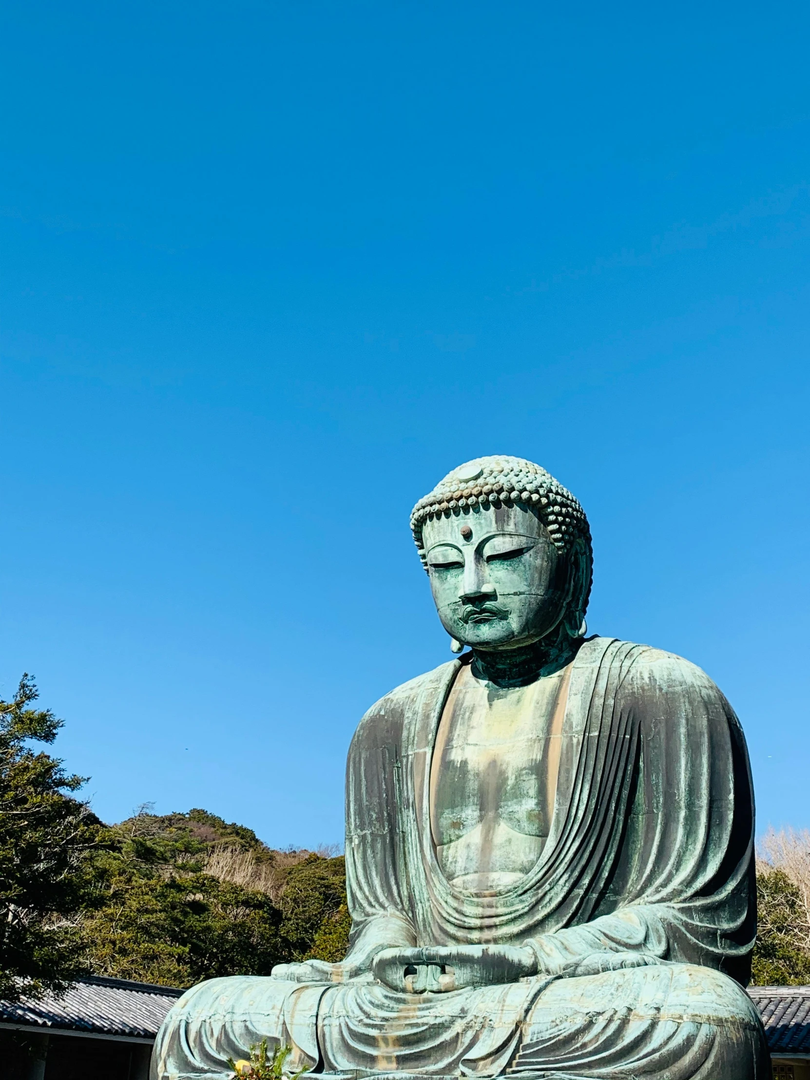 a statue sits in the middle of a garden with tall grass and blue skies