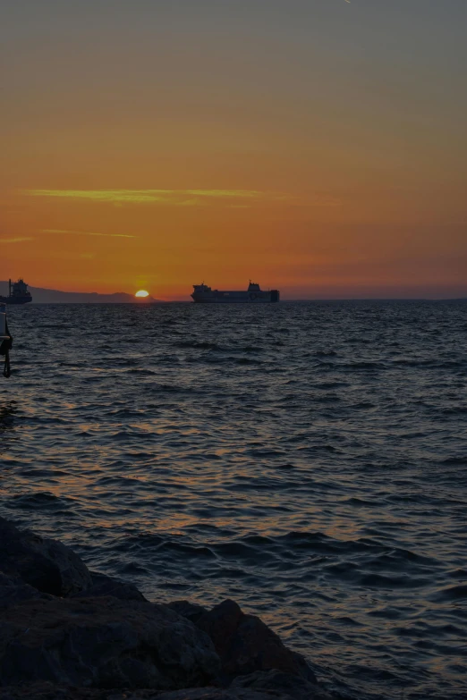 a sunset over a body of water with ships in the distance