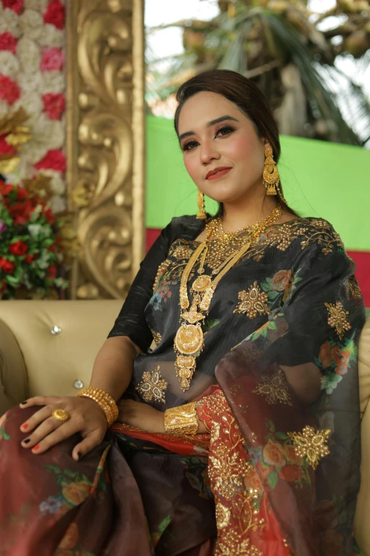 a woman sitting on a couch wearing jewelry and holding onto an orange bag