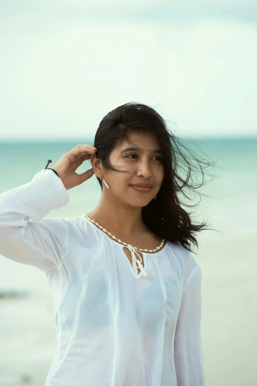 a woman posing on the beach with her hair in the air