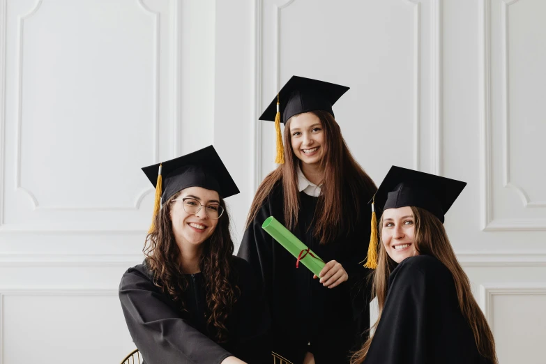 three female graduates pose for the camera in their graduation robes and mortars