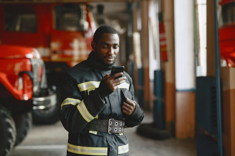 a man holding his cell phone while standing in front of a fire truck