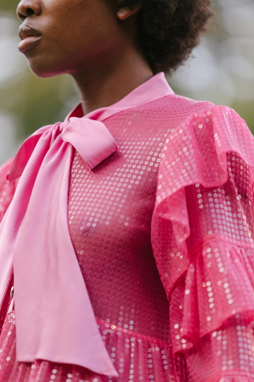 a close up of a woman wearing a pink shirt and a pink bow