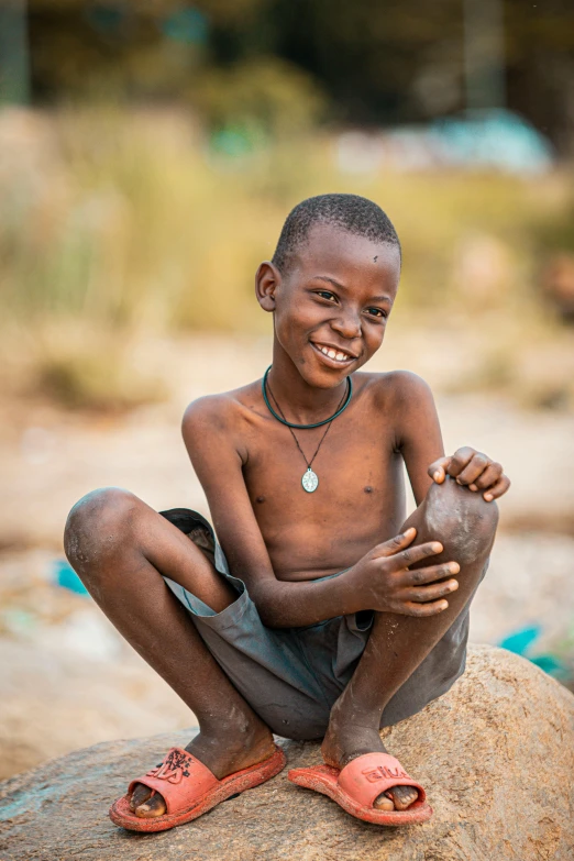 a smiling boy on top of a rock