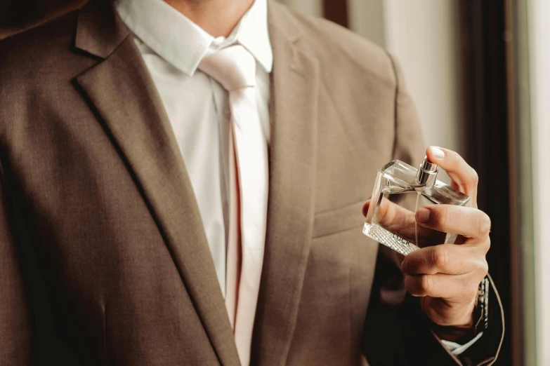 a man in a suit holding a small glass