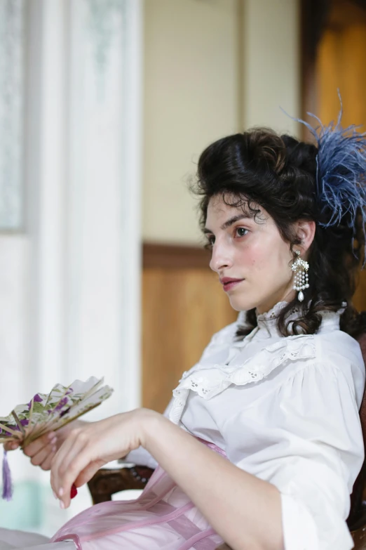 a woman in a white blouse holds a flower and leaves