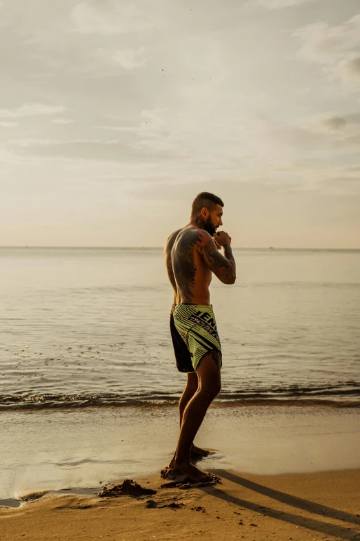 man with tattoos looking at water from beach