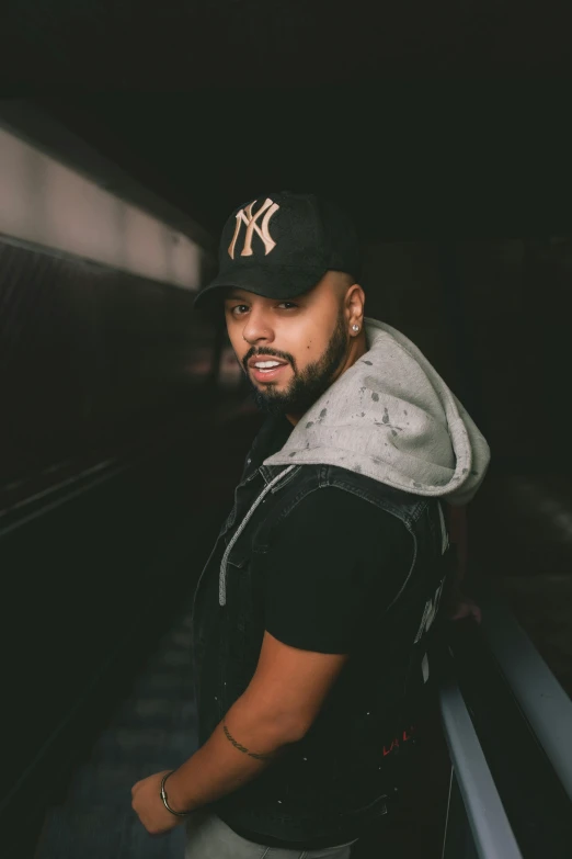 a man wearing a cap, jacket and vest next to a subway