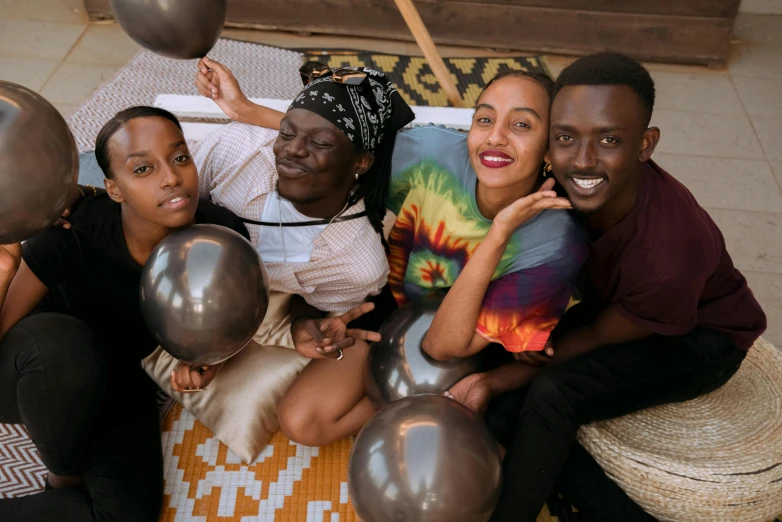 a group of people holding silver metallic balloons