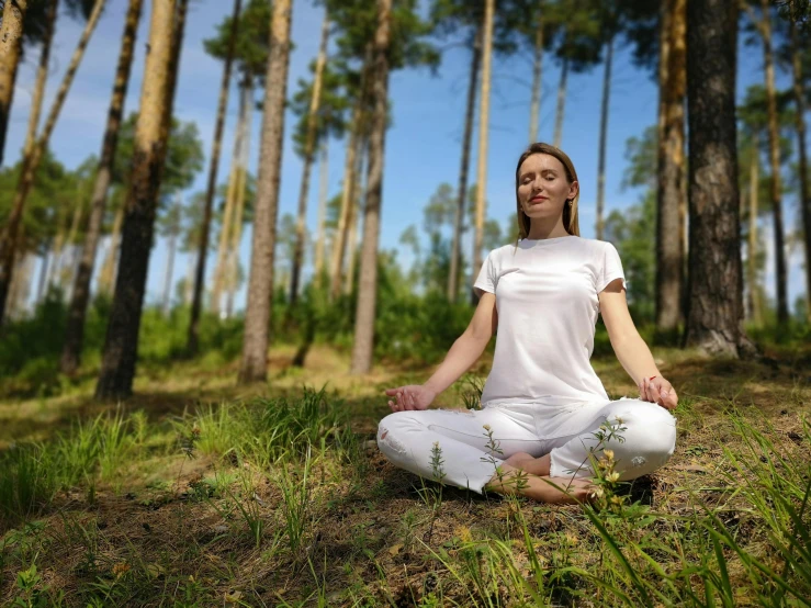 a woman sitting in a forest with her eyes closed