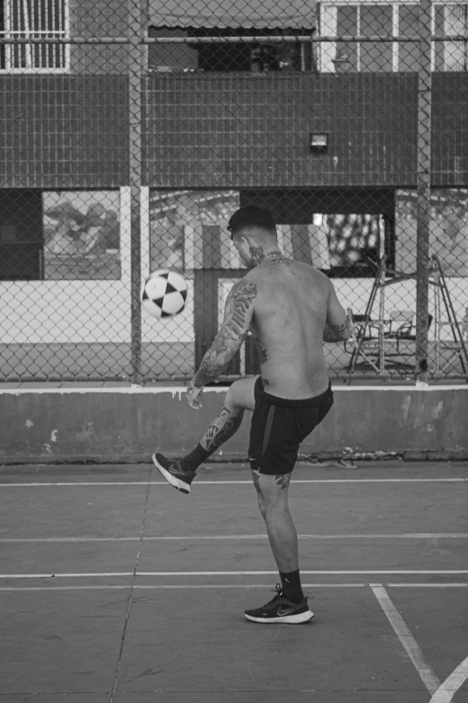 a man is hitting a soccer ball in a parking lot