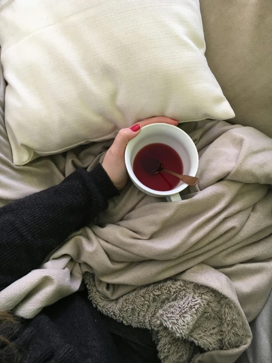 a woman holding a cup of red wine sitting on a couch
