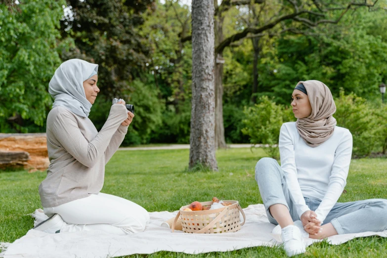 two women sitting on a blanket eating food