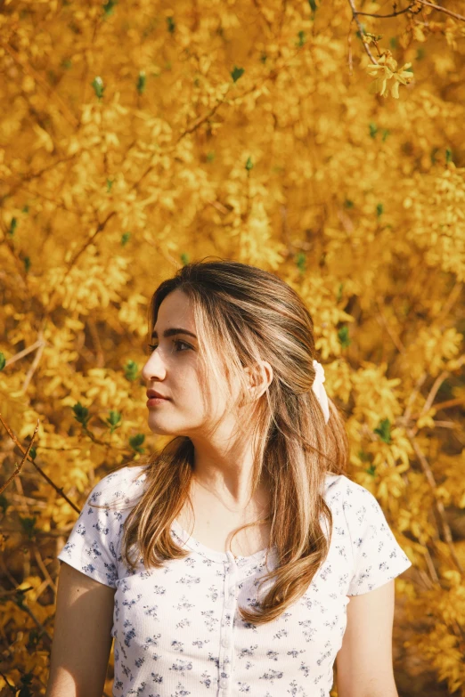 a beautiful young woman standing in front of yellow flowers