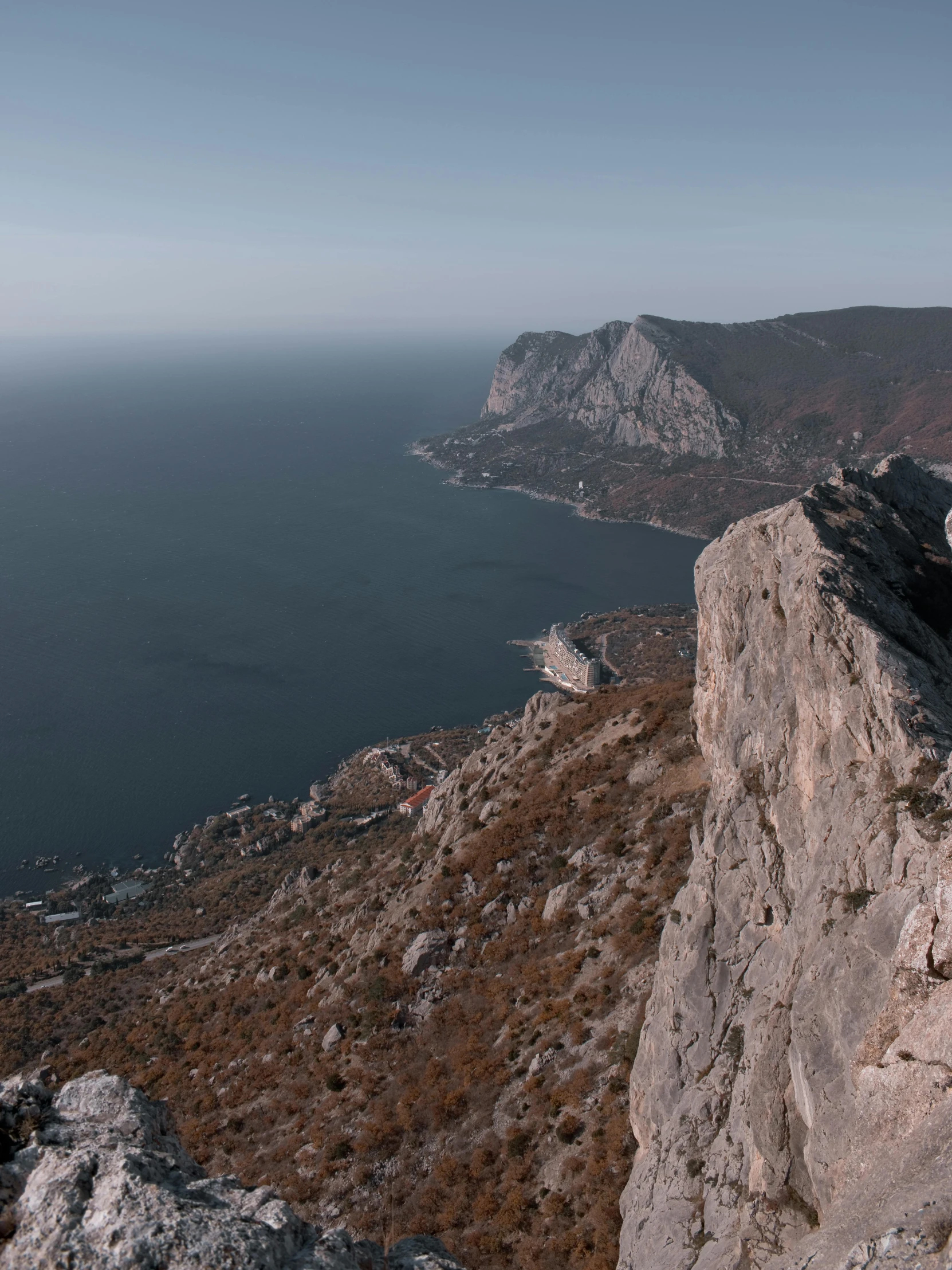 a man sitting on top of a rock next to a cliff