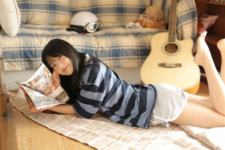 young asian girl reading a magazine while lying on the floor