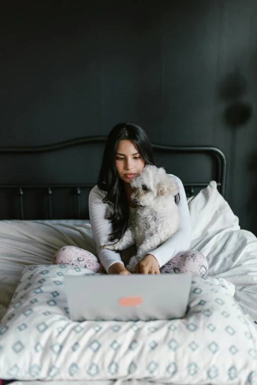 a woman sitting in bed while using her laptop