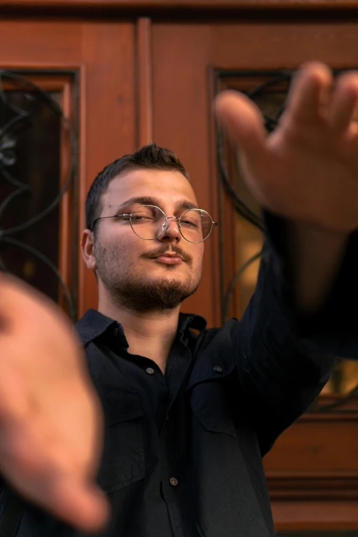 man wearing glasses in front of a wooden door