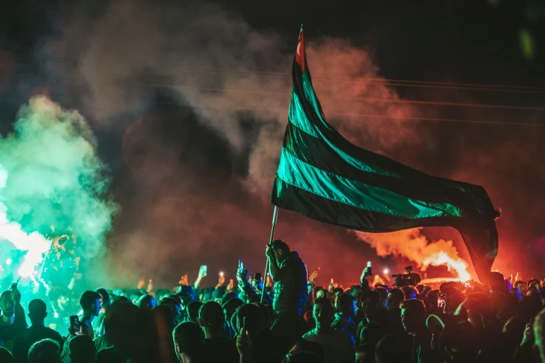 a crowd in front of a large green and red flag