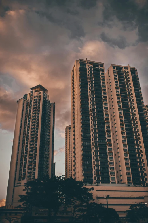 two tall buildings stand against the cloudy sky