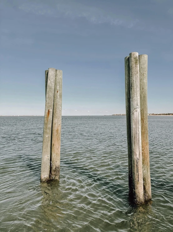 wooden posts sticking out of the water are seen in the ocean