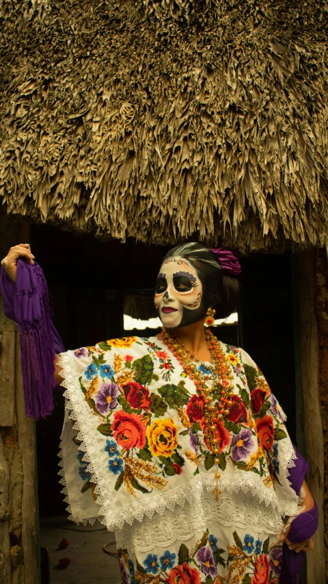 a woman with painted face in front of a thatch hut