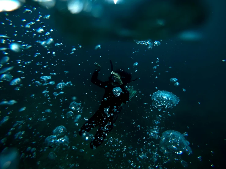 a person diving next to large bubbles in the water