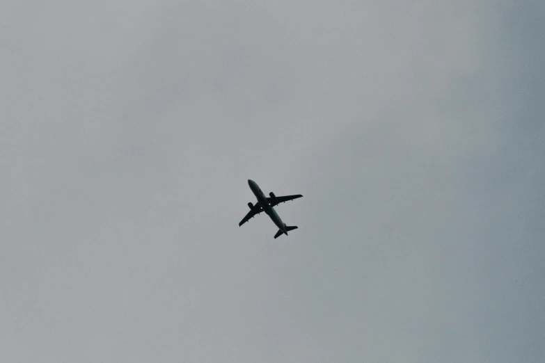 a plane flying through a gray sky during the day