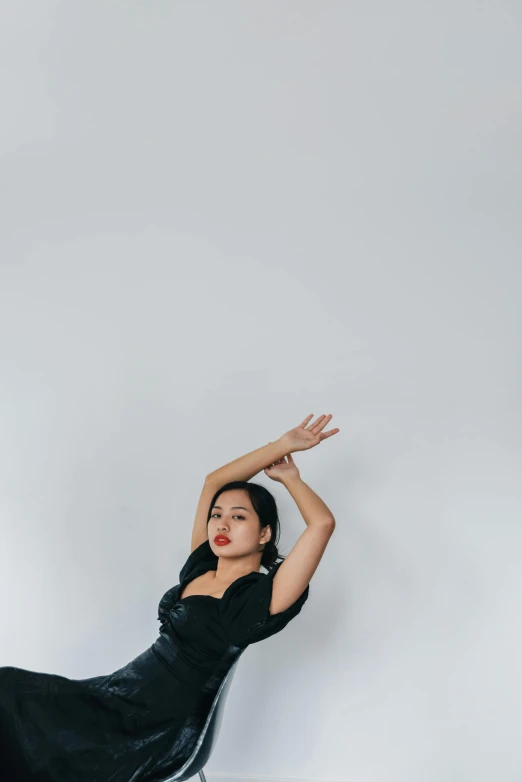 a woman in a black dress leaning back with her legs over the table