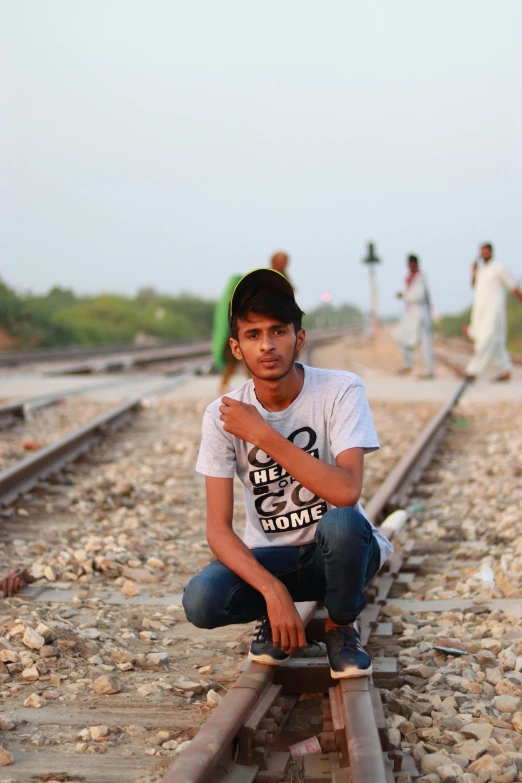 an indian boy is kneeling on train tracks