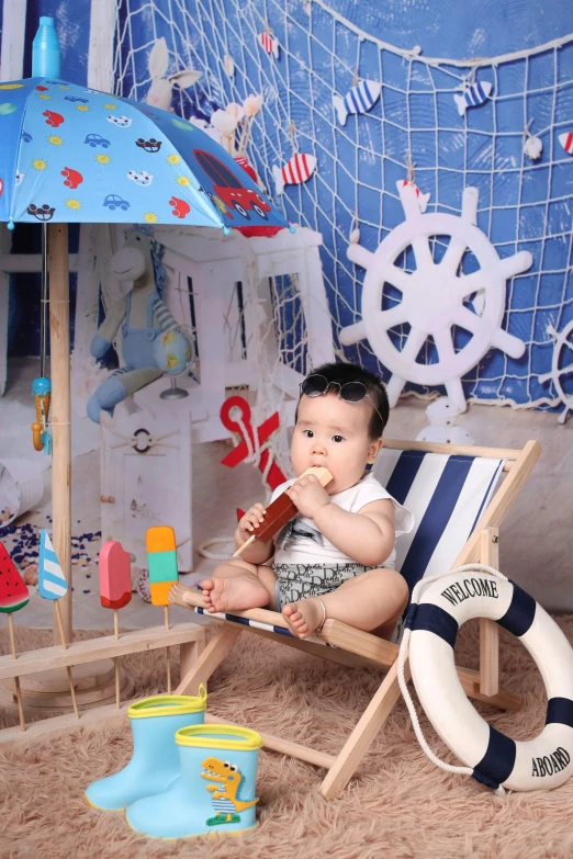 a baby sitting in a beach chair next to an umbrella