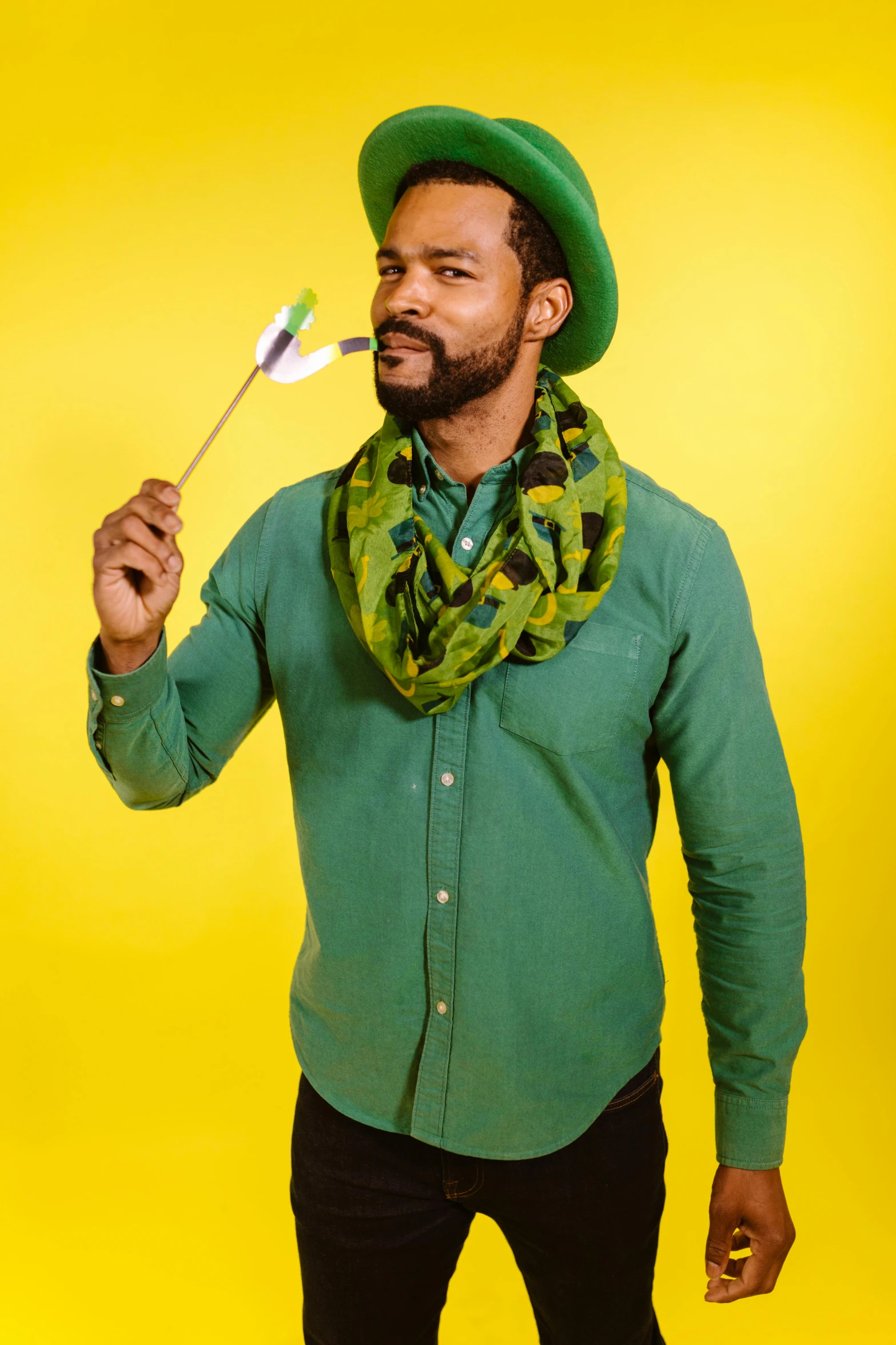 a man with a green hat, sweater and scarf is holding a toothbrush