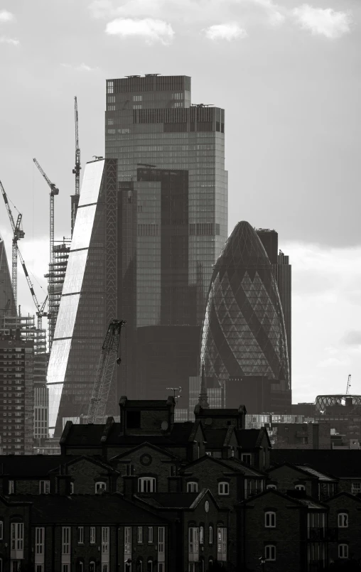 black and white po of tall buildings with cranes on them