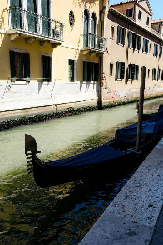 an empty gondola floats through a canal of water