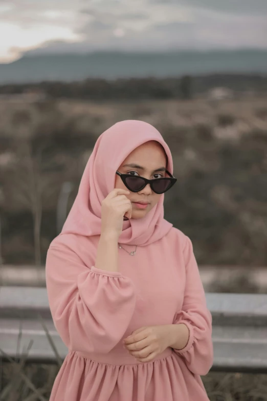 a woman wearing a hijab is holding her nose to her side