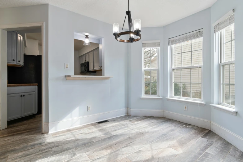 an empty living room with three windows and a hardwood floor