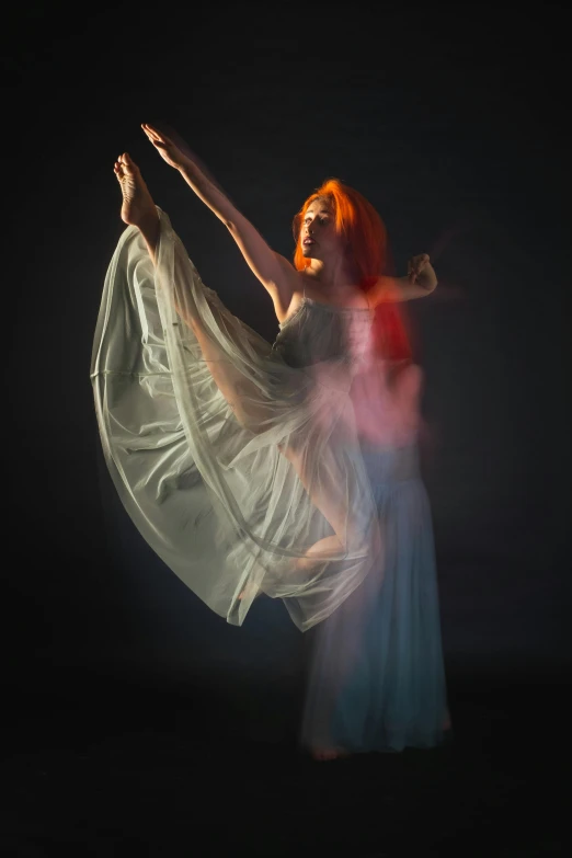 a woman dances with a white cloth flowing across her body